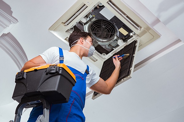 engineer painting ceiling duct wearing face mask