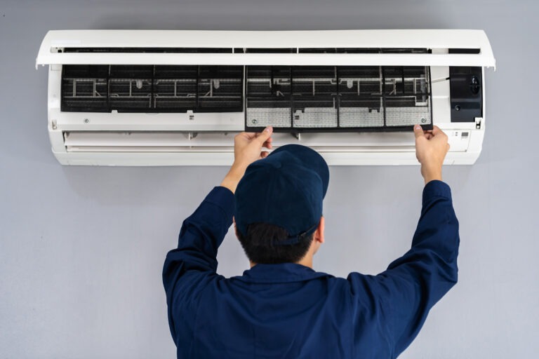 technician in all blue fixing air con unit